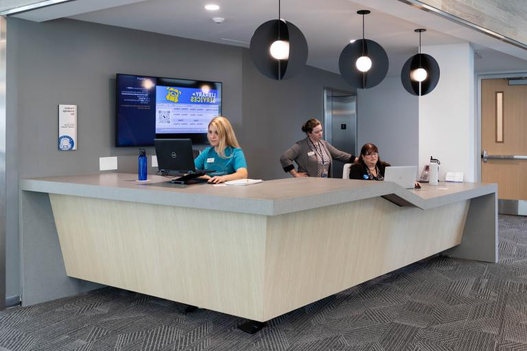 The welcoming library services desk at the Learning Commons provides support and resources to enhance the student experience.