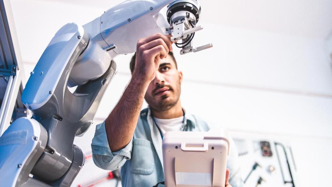 Co-op student working on an automated manufacturing robot arm