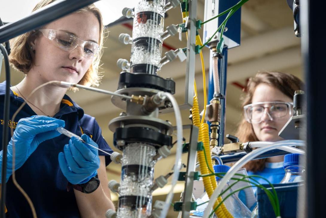 Two Kettering chemical engineering students insert liquid into lab equipment in the Chemical Engineering Teaching Lab