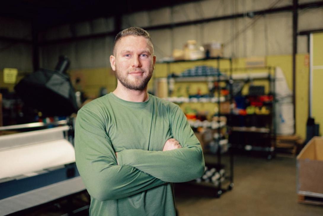 Kettering alum Peter Deppe stands with arms crossed inside a Kettering garage