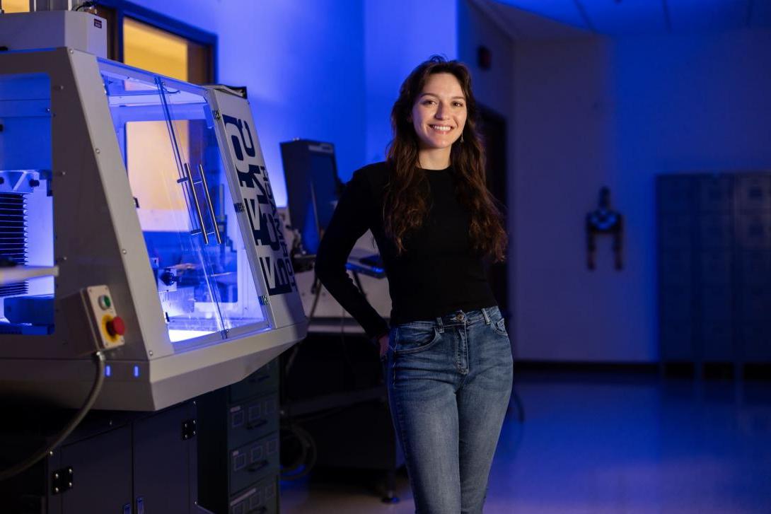 A Kettering student stands next to a CNC mill in the Hougen Design Studio